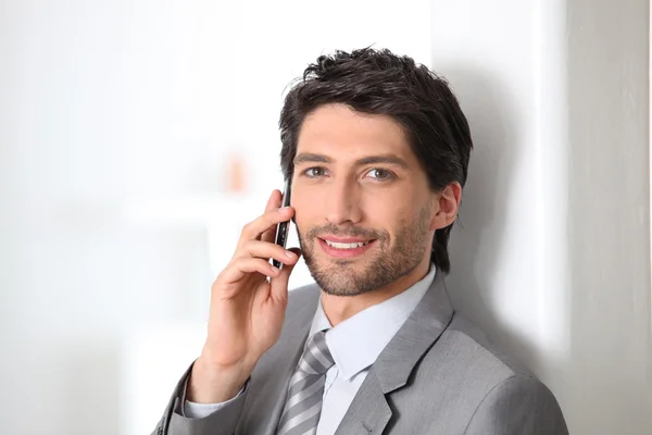 Un hombre de negocios sonriente usando un teléfono celular — Foto de Stock