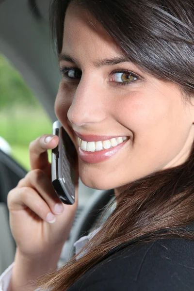 Brunette op een mobiele telefoon in een auto — Stockfoto