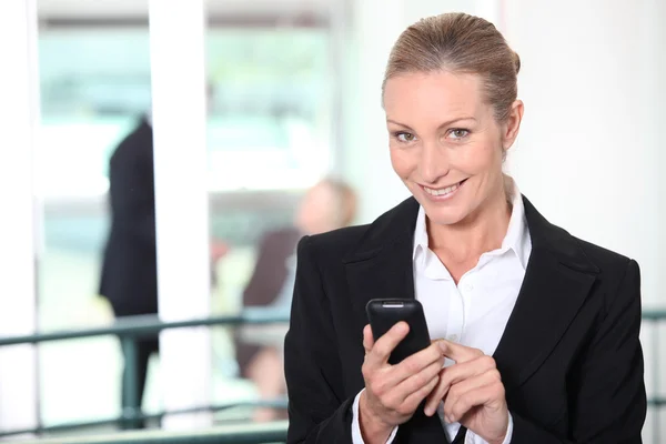Üzletasszony egy mozgatható telefon-val mosolyog — Stock Fotó