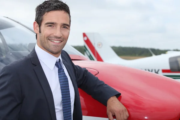 Jovem empresário em pé na frente de um avião — Fotografia de Stock