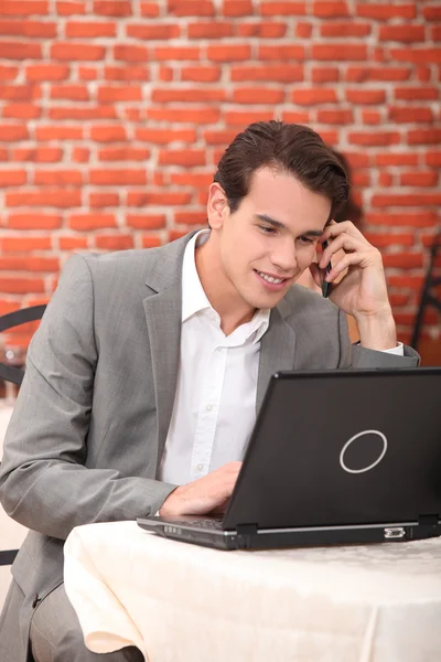 Young man using a laptop in a restaurant — Stock Photo, Image