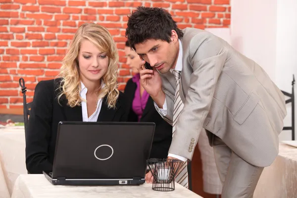 Uomo su un cellulare e donna su un computer portatile — Foto Stock