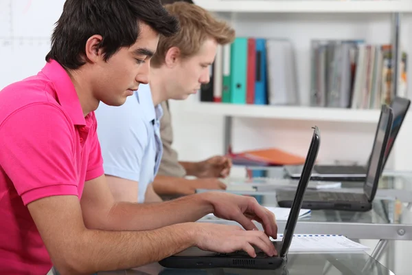Jovens estudantes do sexo masculino em sala de aula trabalhando em laptops — Fotografia de Stock