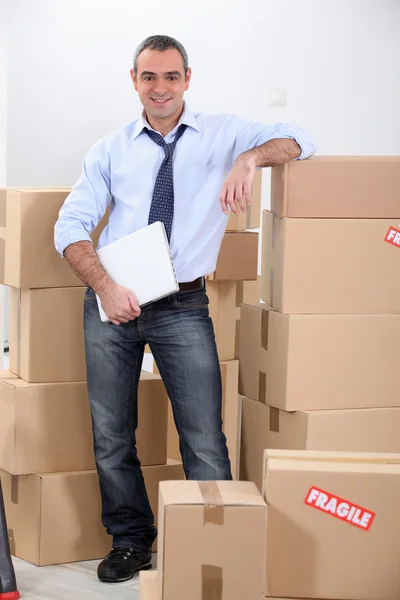 Courrier stood by stacked boxes — Stock Photo, Image