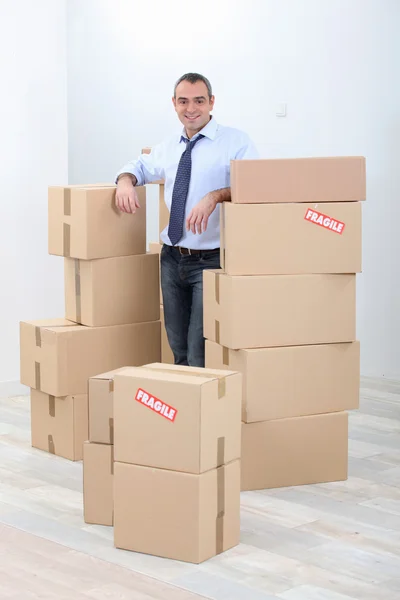 Man with piles of cardboard boxes marked fragile — Stock Photo, Image
