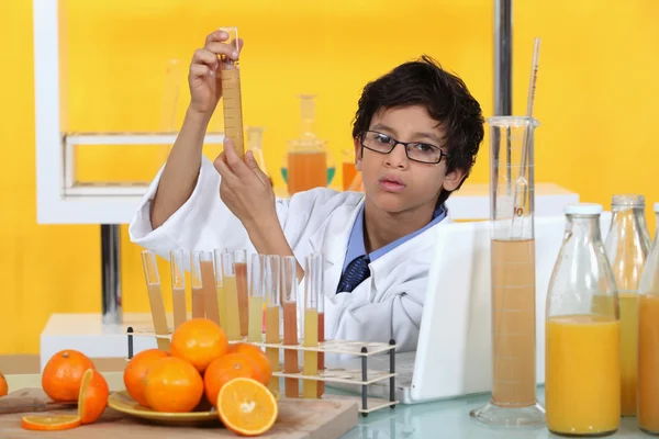 Liten pojke genomför experiment på apelsinjuice — Stockfoto