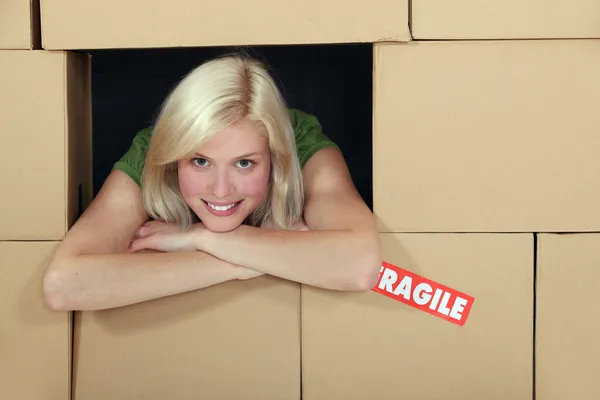 Frau von einer Wand aus Verpackungskartons umgeben — Stockfoto