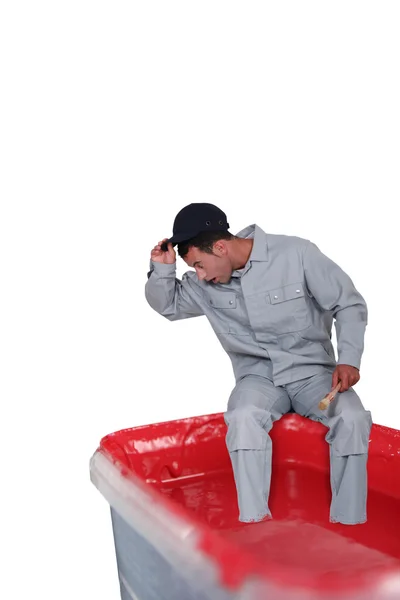 Verrast man zit op een verf kan — Stockfoto