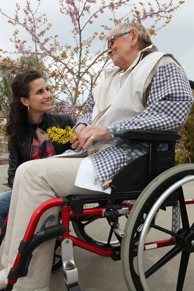 Ung kvinna med en äldre dam i en rullstol — Stockfoto