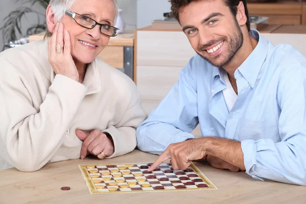 Játszani a játékot, idős nő fiatal férfi — Stock Fotó