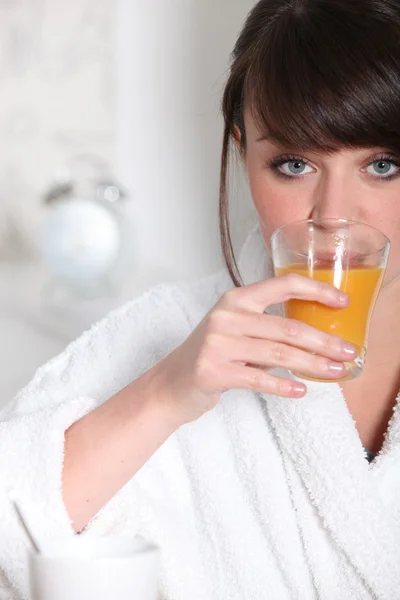 드레싱 가운 오렌지 주스 잔을 들고 있는 여자 — 스톡 사진