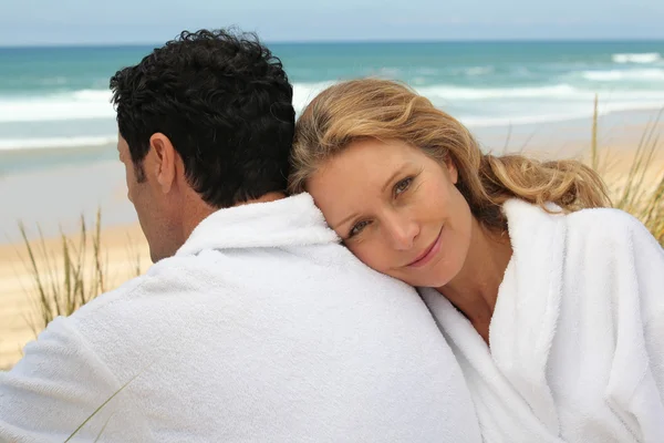 Een man en een vrouw kamerjassen dragen op een strand. — Stockfoto