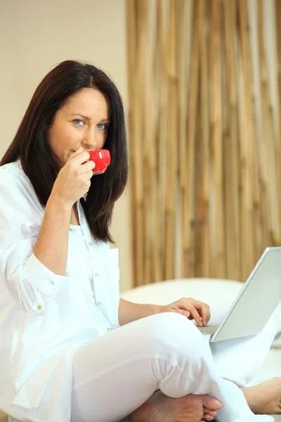 Mulher madura bebendo seu café e enviando emails — Fotografia de Stock