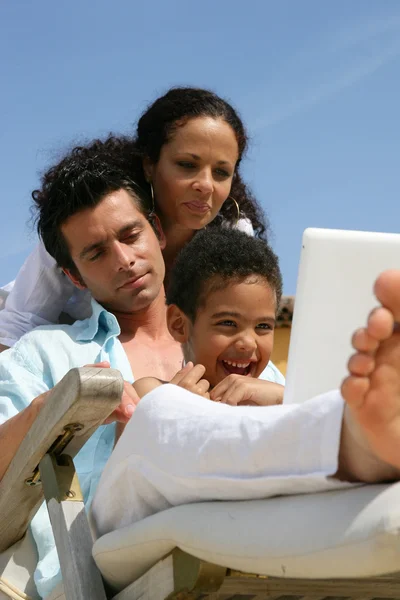 Homme, femme et petit garçon utilisant un ordinateur portable sur un transat — Photo