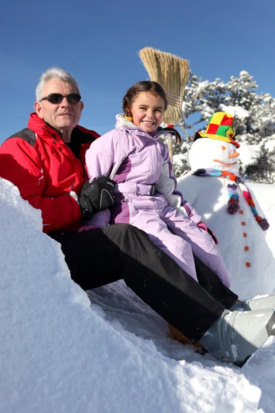 Батько і дочка зі сніговиком — стокове фото