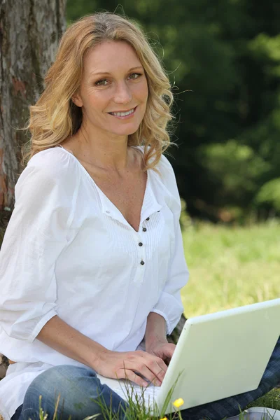 Kobieta na laptopie pod drzewem — Zdjęcie stockowe