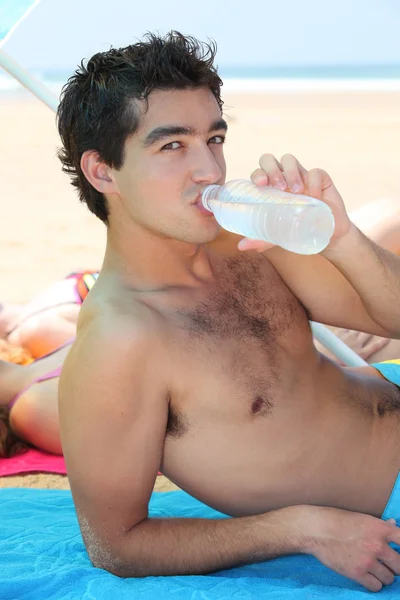 Підліток п'є воду на пляжі — стокове фото