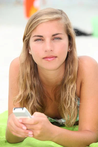 Eine junge Frau, die am Strand SMS schreibt. — Stockfoto