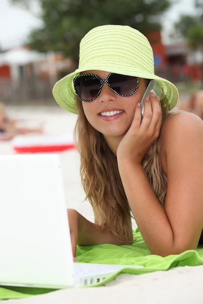 Jonge vrouw met behulp van technologie op het strand — Stockfoto