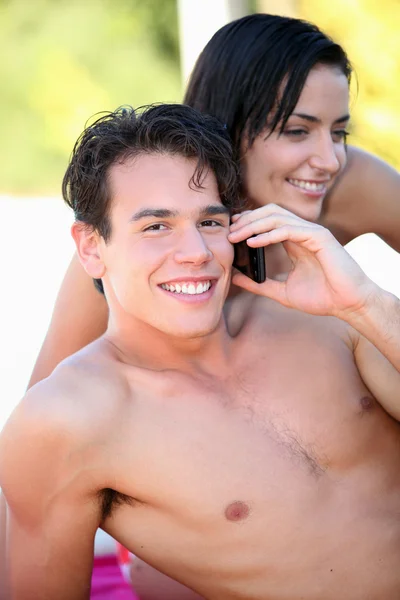 Bare-chested boy phoning with girlfriend by his side — Stock Photo, Image
