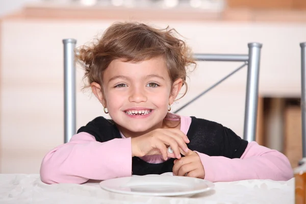 Menina sorrindo à mesa para lanche da tarde — Fotografia de Stock