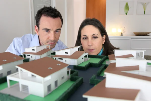 Casal olhando para um modelo de uma propriedade de habitação — Fotografia de Stock