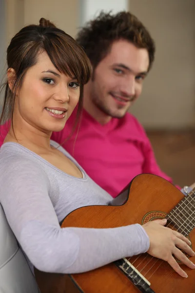 Kobieta grająca na gitarze dla swojego chłopaka — Zdjęcie stockowe