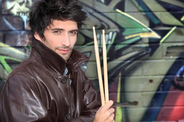Musician with drumsticks against graffiti wall — Stock Photo, Image