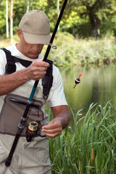 Homme regardant sa canne à pêche devant une rivière — Photo