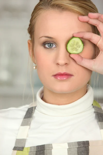 Vrouw haar oog met plakje komkommer verbergen — Stockfoto