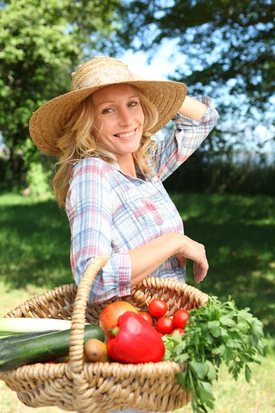 Mulher bonita com um chapéu de palha e cesta de legumes . — Fotografia de Stock