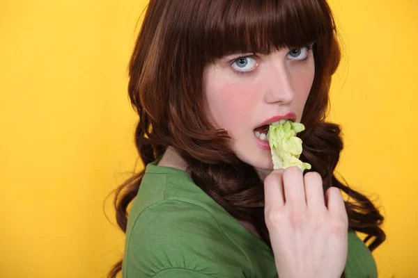 Morena comendo folha de alface — Fotografia de Stock