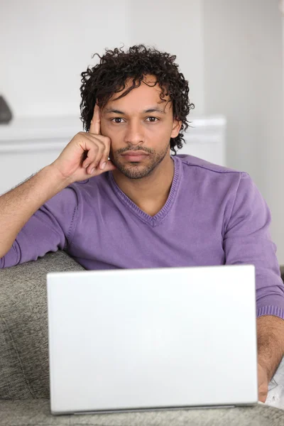男子在他家的沙发上使用一台笔记本电脑 — 图库照片