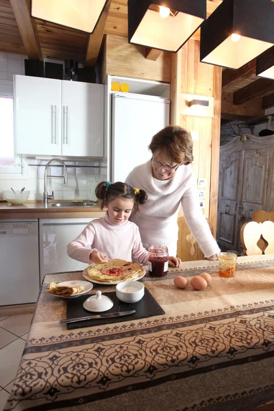 Маленькая девочка и бабушка готовят блинчики — стоковое фото