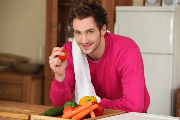 Man i köket håller tomat — Stockfoto
