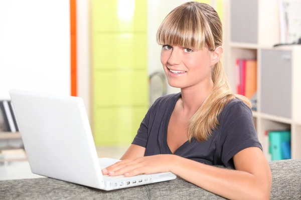 Een jonge vrouw met haar laptop op haar bank. — Stockfoto