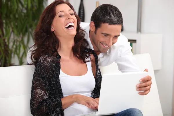 Пара смеется над своим ноутбуком — стоковое фото