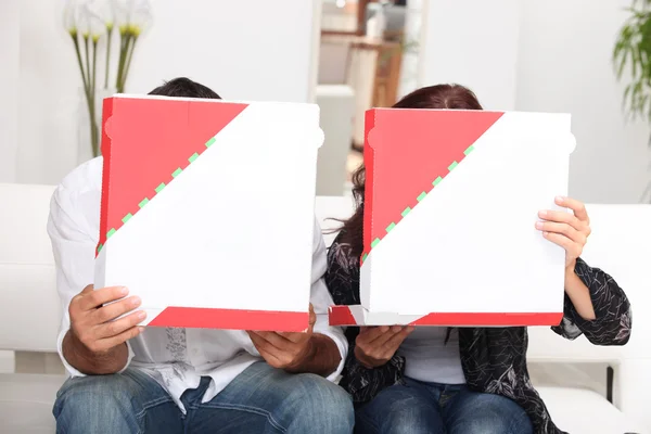 Couple hiding behind pizza boxes — Stock Photo, Image