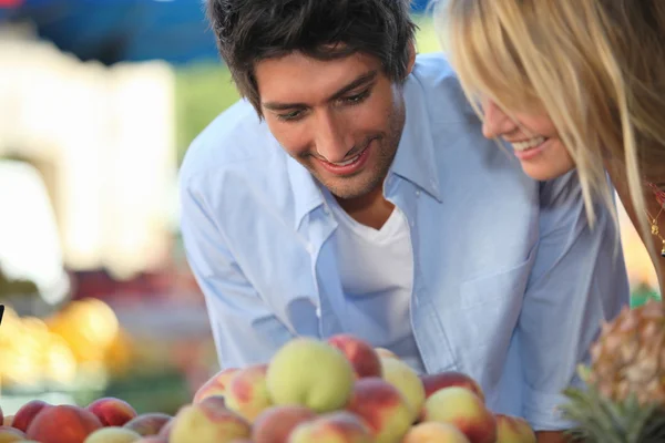 Молода пара купує фрукти на ринку — стокове фото
