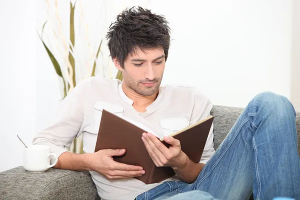 Adam bir kanepenin üzerine bir kitap okuma — Stok fotoğraf
