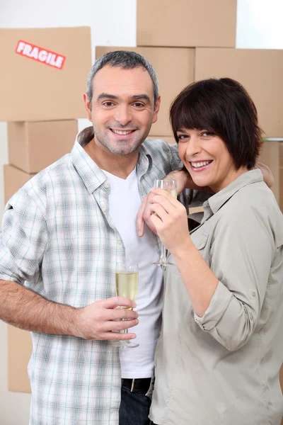 Пара випиває шампанське перед купою картонних коробок — стокове фото