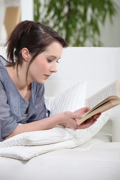 En ung brunett läser en bok. — Stockfoto