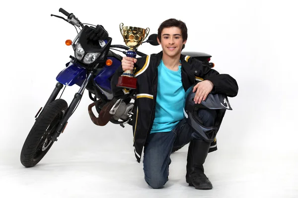 Підліток із золотою чашкою перед мотоциклом — стокове фото