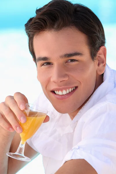 Mladý muž pije pomerančový džus — Stock fotografie