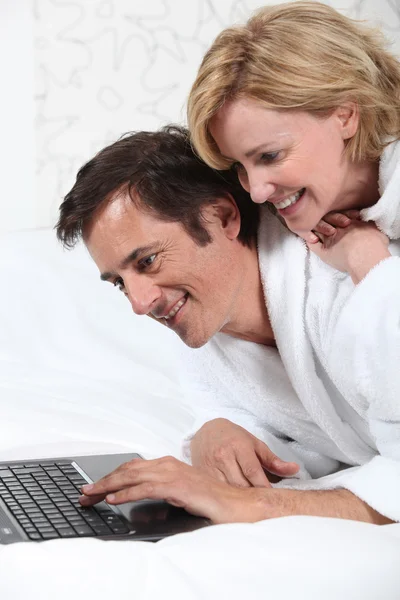 Koppel op laptop in badjas. — Stockfoto