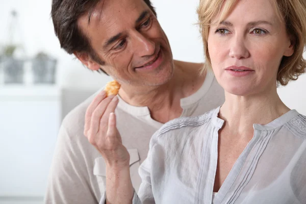 Frau in Küche hält Essen in der Hand Mann schaut sie an — Stockfoto