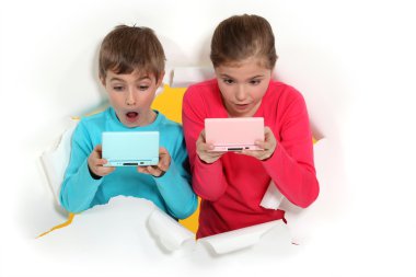 Children playing handheld computer games clipart