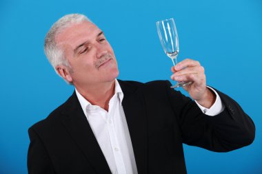 Grey-haired man holding champagne flute clipart