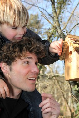 Father and son stood by bird-house clipart