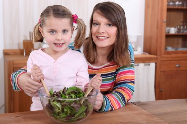 Mother and daughter preparing a salad clipart